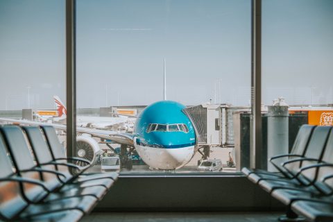 blue plane parked outside airport terminal